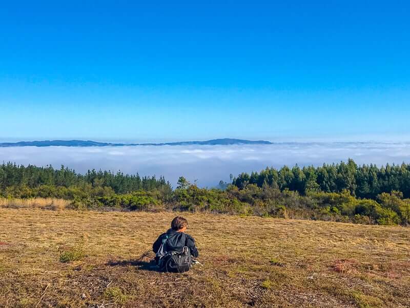 walker resting to enjoy the clouds and far-reaching views on the Camino de Santiago