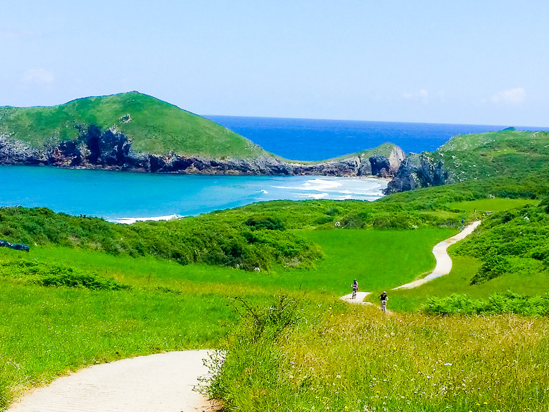 Cyclists on the undulating hills of the Coastal Path near Llanes in Asturias.