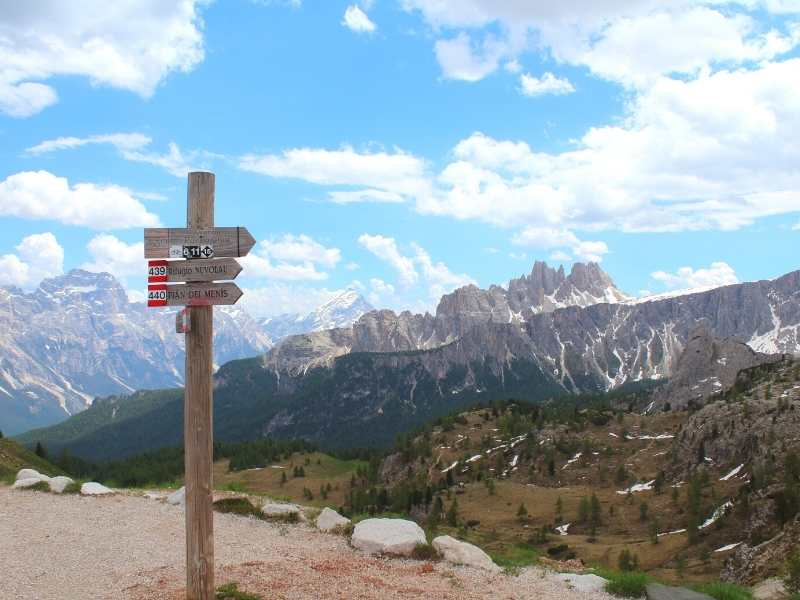 Hiking route signs with the Dolomites Mountain Range on the Alta Via 1 South