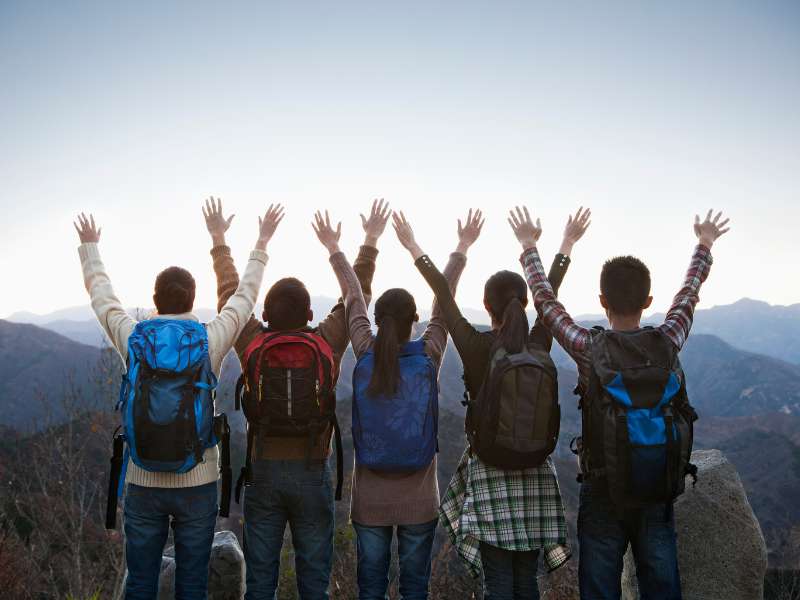 a group of friends celebrating after hiking at the top of the mountains