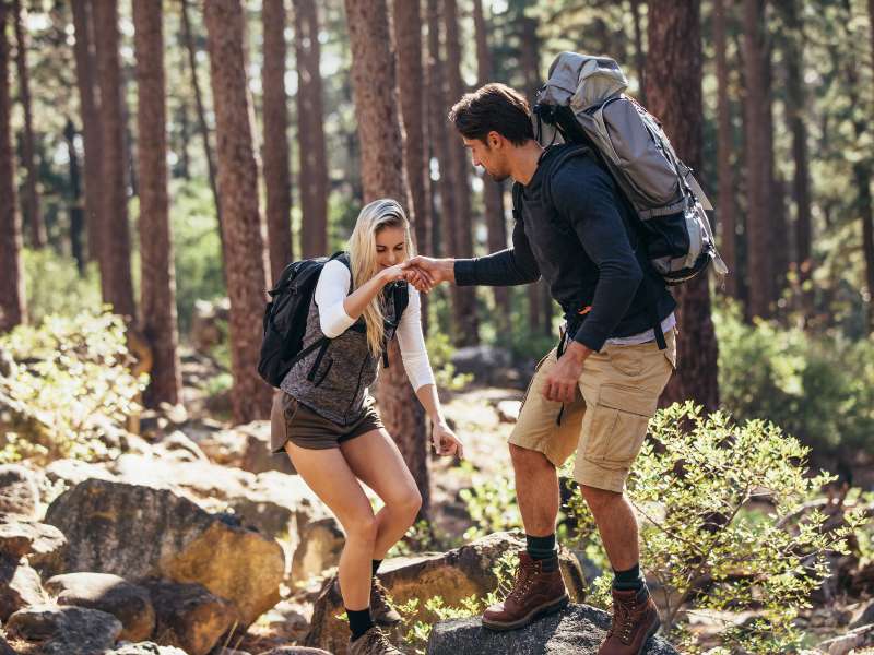 man offering a helping hand to a woman while hiking