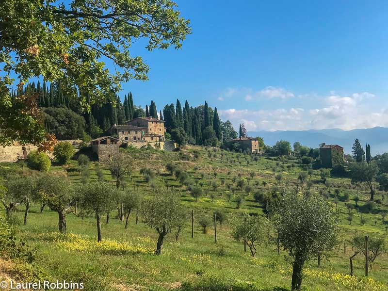 Hikers pass by orchards and farmhouses on the Path of Gods Italy in Tuscany.