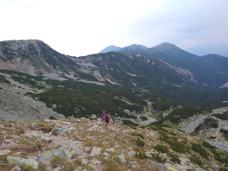 Wanderer, die absteigen, um einen anderen Berggipfel zu erreichen und zu besteigen