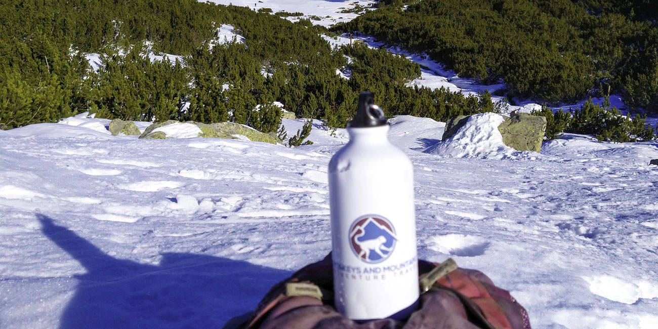 Monkeys and Mountains water bottle at the top of a snowy mountain