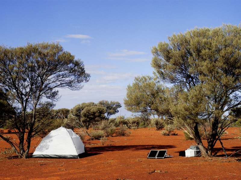 hiking tent set up near a solar charger under the heat of the sun