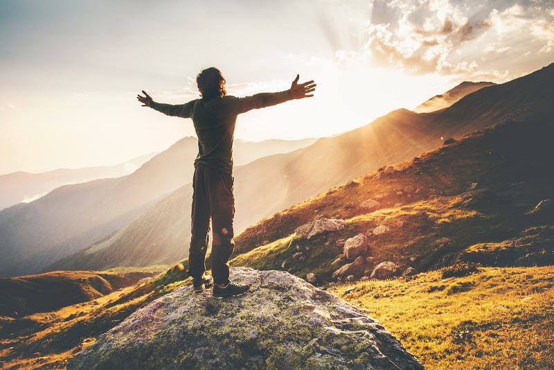 man celebrating after reaching the mountain peak