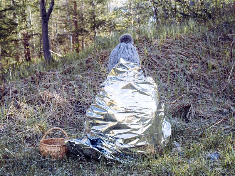 woman wearing survival thermal blanket on hike