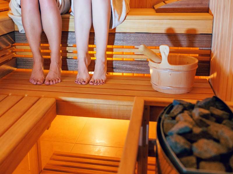 women sitting in sauna with bucket and stones