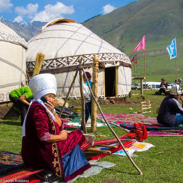 Kyrgyz woman on her mobile phone while weaving at the World Nomad Games