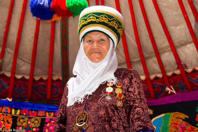 A Kyrgyz woman in traditional nomadic clothing inside her yurt. 